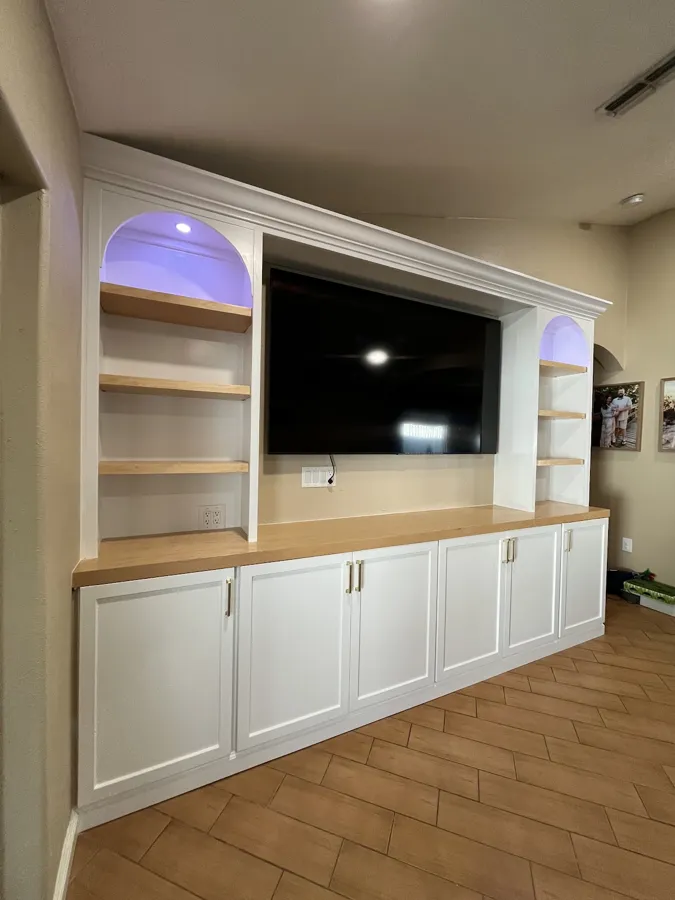 White built-in entertainment center with arched lit shelves and a wood countertop, Tampa, FL